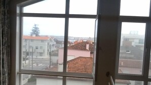 Una ventana con vista a una zona residencial, con casas y una calle.