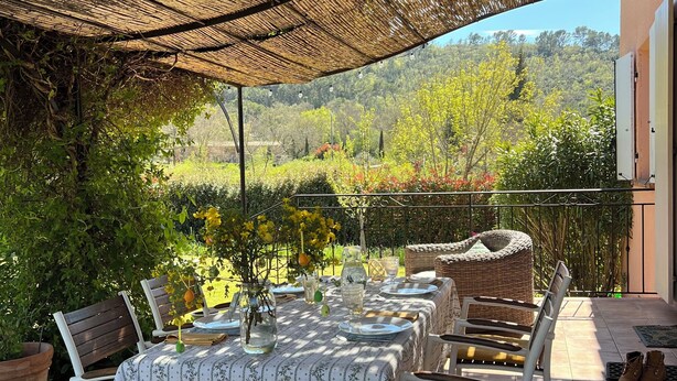 An outdoor dining area with a table set for four, surrounded by chairs, under a woven canopy. - La Villa Rose is a spacious villa in Provence with a large pool. (Le Thoronet)