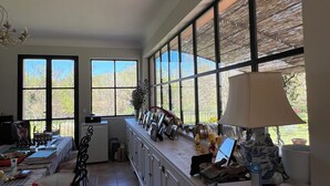 A kitchen with large windows, a dining table, and a refrigerator. - La Villa Rose is a spacious villa in Provence with a large pool. (Le Thoronet)