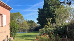 A garden with a variety of plants and flowers, a tall tree, and a building with a tiled roof. - La Villa Rose is a spacious villa in Provence with a large pool. (Le Thoronet)
