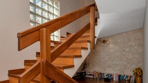 A wooden staircase with a stone wall and a shelf with books and a vase. - Villa With Large Terrace  (Podgora)
