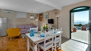 A dining area with a table set for four, a sofa, and a television mounted on the wall. - Villa With Large Terrace  (Podgora)