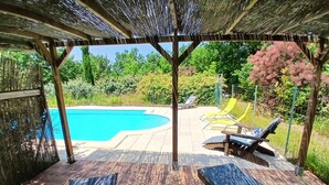 A covered outdoor area with a pool, lounge chairs, and a wooden deck. - Gite Le Sabatou. Converted Barn, Private Pool, 15ha ASPAS Nature Park. (Cézac)