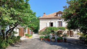 A stone building with a tiled roof, surrounded by gravel paths and potted plants. - Gite Le Sabatou. Converted Barn, Private Pool, 15ha ASPAS Nature Park. (Cézac)