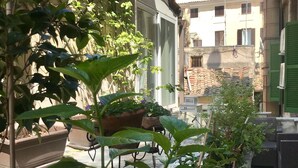 A courtyard with potted plants, a bench, and a building in the background. - Count Checco. A heaven in the rooftops of Rome few steps away from the pantheon (Roma)