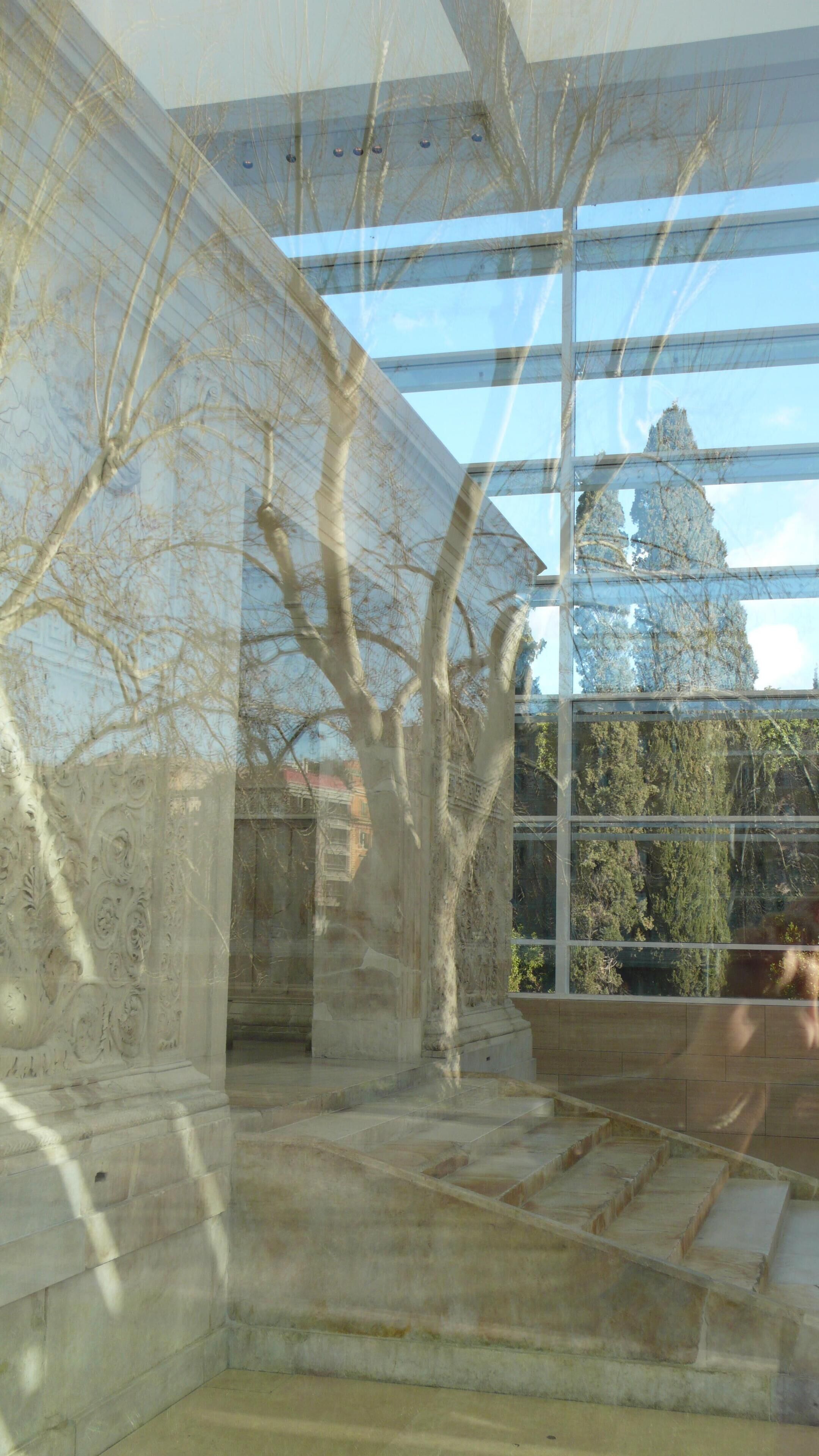 Ein modernes Gebäude mit großen Glasfenstern, einer Stein-Fassade und Blick auf Bäume und andere Gebäude.