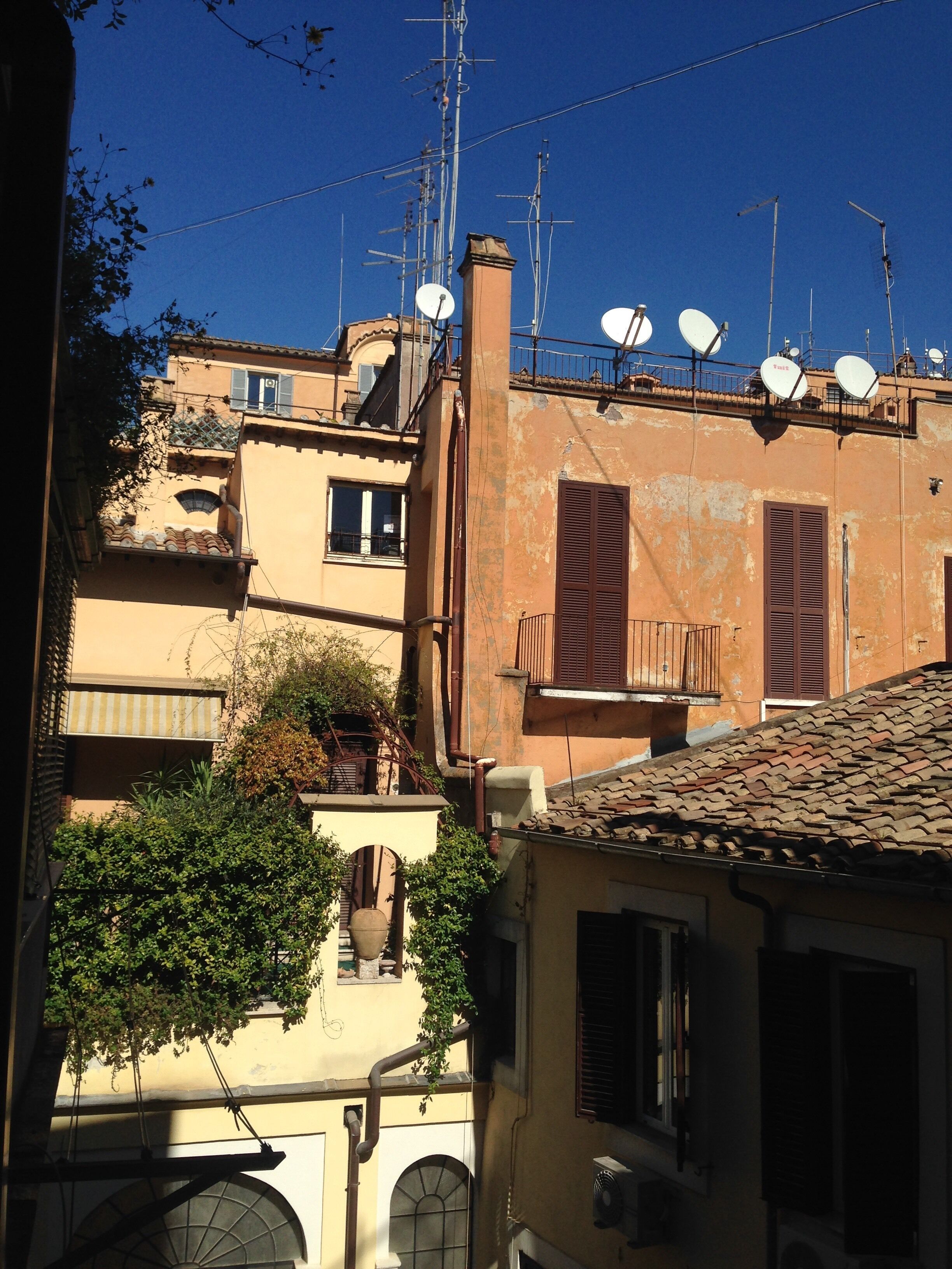 A building with multiple satellite dishes, a large window, and a visible chimney.