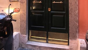 A black door with a brass handle, a motorcycle parked to the left, and a number '24' sign on the wall. - Count Checco. A heaven in the rooftops of Rome few steps away from the pantheon (Roma)