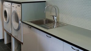 A modern kitchen with white cabinets, a stainless steel sink, and a built-in washing machine. - Modern newly built house, 187 sqm with large balcony (Huddinge)
