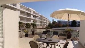 A balcony with a round table, chairs, and a large umbrella. - Lovely Townhouse on Lagos Marina with swimming pool, Air Con & WiFi (LAGOS, Algarve)
