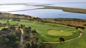 A golf course with a water body in the background. - Lovely Townhouse on Lagos Marina with swimming pool, Air Con & WiFi (LAGOS, Algarve)