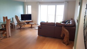 Ett vardagsrum med en soffa, en tv och en matplats.