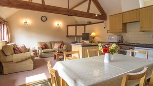 Una sala de estar acogedora con una mesa de comedor, dos sofás y una zona de cocina con armarios de madera y un microondas.