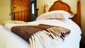 Una cama con una manta marrón y blanca, un cabecero de madera y un almohadón blanco.