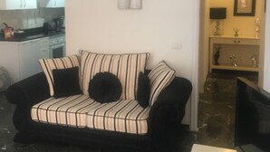 A living room with a black and white striped sofa, a flat-screen TV, and a marble floor. - Superb apartment with stunning sea and cliff views, 2 terraces and free wifi. (Santiago del Teide)
