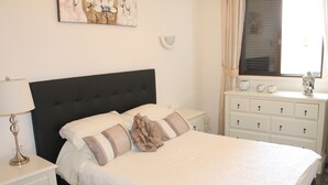 A neatly made bed with a dark headboard, a bedside table with a lamp, and a dresser with drawers. - Superb apartment with stunning sea and cliff views, 2 terraces and free wifi. (Santiago del Teide)