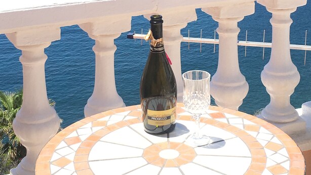 A bottle of Prosecco wine on a tiled table with a glass, overlooking a coastal sea with cliffs. - Superb apartment with stunning sea and cliff views, 2 terraces and free wifi. (Santiago del Teide)