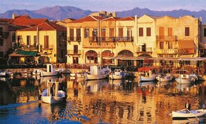 Une promenade en bord de mer avec des bateaux amarrés, des immeubles dotés de balcons et un restaurant appelé « Ero Torizos ».