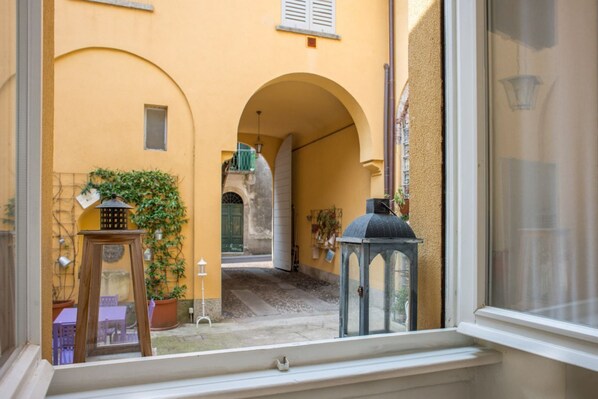 A courtyard with a wooden table, potted plants, and a lantern.