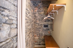 A narrow hallway with a stone wall on one side and a wooden bench on the other.