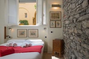 Une chambre d’hôtel avec un lit, une fenêtre, un mur en pierre et des tableaux encadrés accrochés au mur.