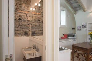 A kitchen with a stone wall, a microwave, and a sink.