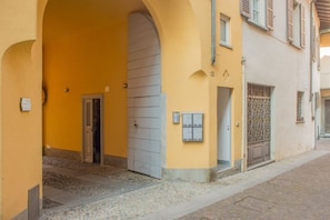 A building with a yellow facade, a large arched entrance, and a cobblestone street.