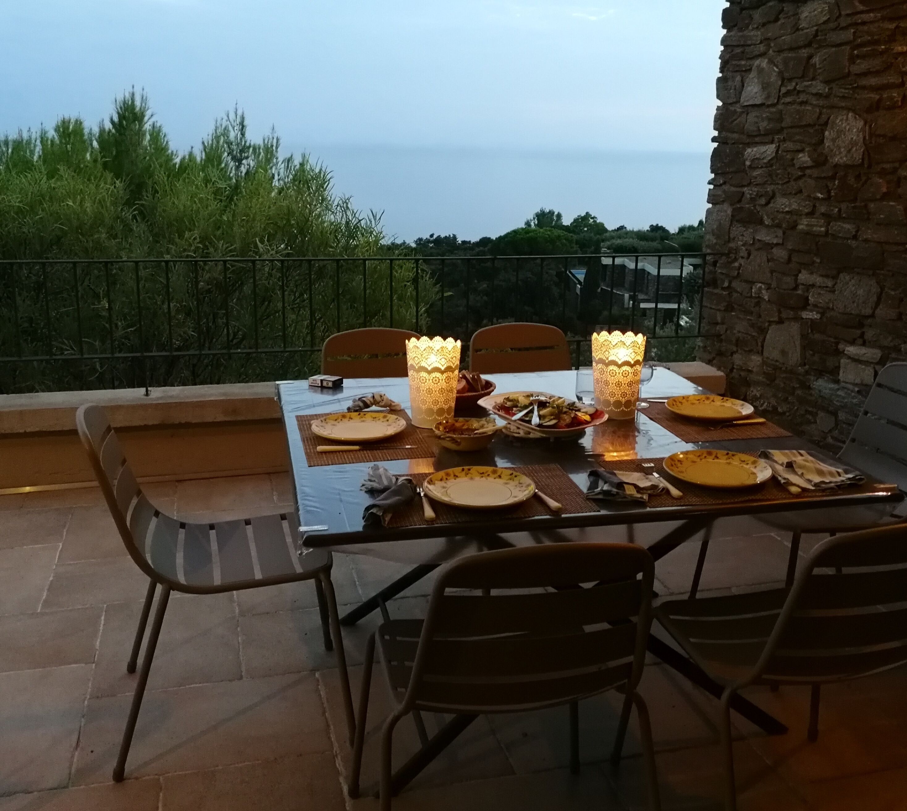 A table set for a meal on an outdoor patio with a view of the sea.