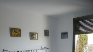 Ein Schlafzimmer mit einem großen Bett, einem Nachttisch und einem Fenster mit Blick ins Freie.