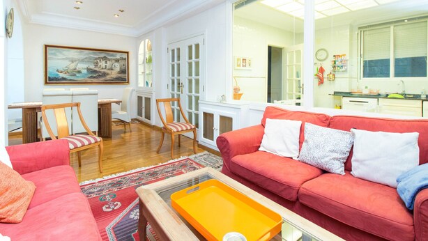 Un salon spacieux avec un canapé rouge, une table basse en bois et un tableau accroché au mur.