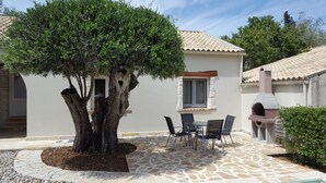 Eine Terrasse mit Steinböden, einem Tisch und Stühlen sowie einem Baum.
