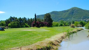 Ein Golfplatz mit Teich und einem Berg im Hintergrund.
