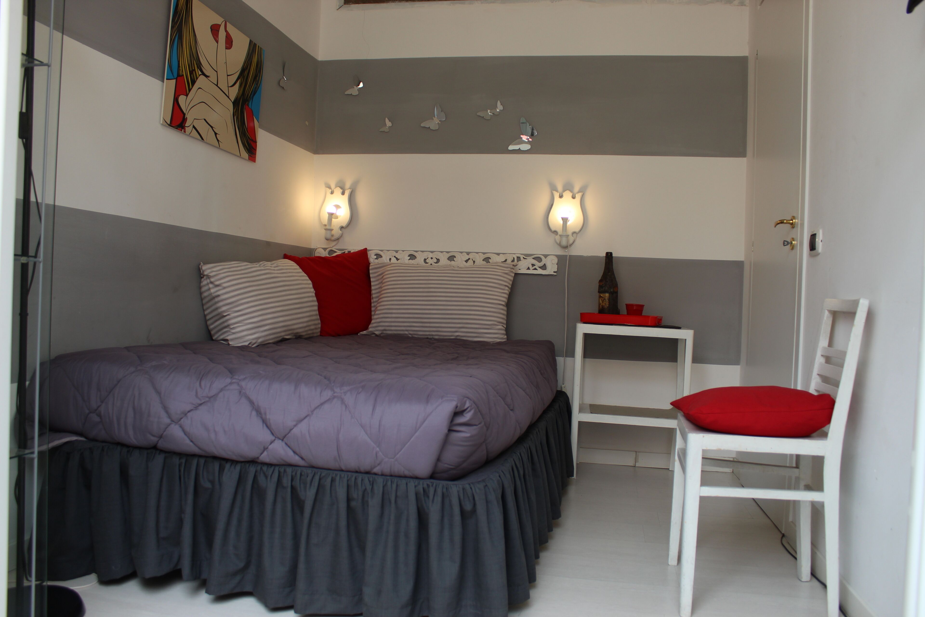 Une chambre à coucher avec un grand lit, une chaise, une table de chevet et des appliques murales.
