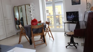 A dining area with a table, chairs, a mirror, a television, and a piano. - Naples city of the Sun and the Sea and 2500 years of history awaits you (Napoli)