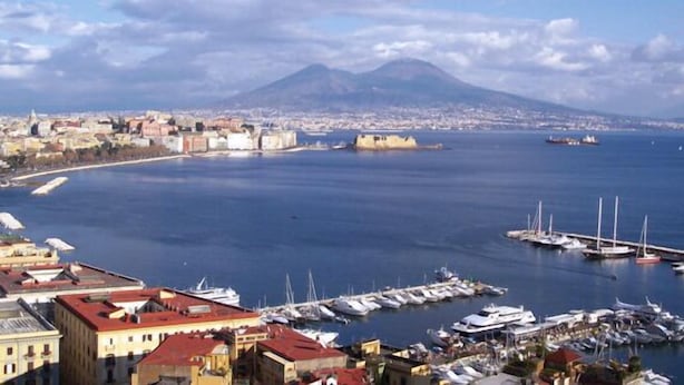 A coastal cityscape with a marina, buildings, and a mountain in the background. - Naples city of the Sun and the Sea and 2500 years of history awaits you (Napoli)