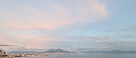 Un paisaje urbano costero con vista al mar y montañas distantes.