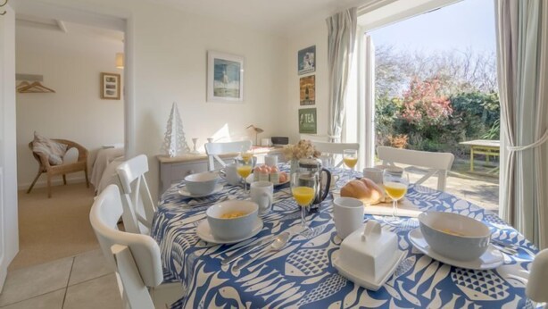 Een ontbijttafel gedekt met kommen, borden en glazen, met uitzicht op groen buiten.