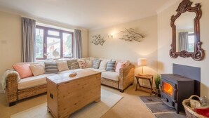 Een gezellige woonkamer met een bank, een houten salontafel, een open haard en een spiegel aan de muur.