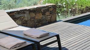 Eine Holzterrasse mit einer Steinmauer und einem Pool.