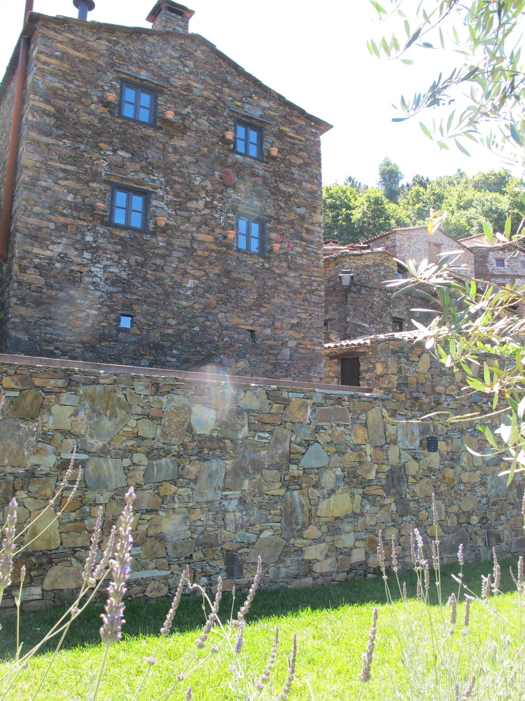 A stone building with multiple windows and a stone wall in front.