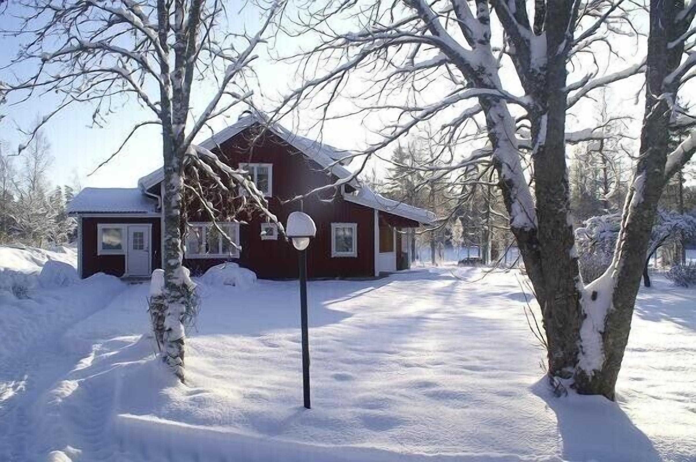 Una casa roja con techo nevado y una puerta principal visible.