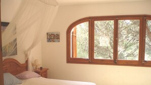A bedroom with a bed, a nightstand, a window, and a painting on the wall.