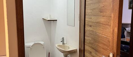 A small bathroom with a toilet, sink, and mirror.