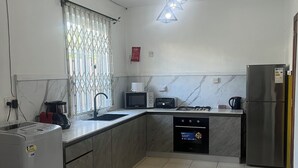 A kitchen with a microwave, toaster, sink, and refrigerator. - Flic En Flac: Furnished 2 bedrooms  1 min walk from beach with WIFI & Nespresso (Flic- en-Flac)