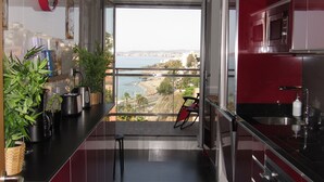 Une cuisine moderne avec vue sur la mer, des placards rouges et une horloge rouge.