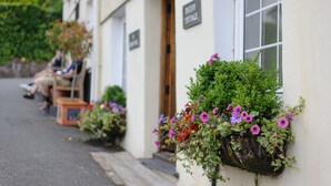 A building with a sign reading "Duchy Cottage" and flower boxes on the exterior wall.