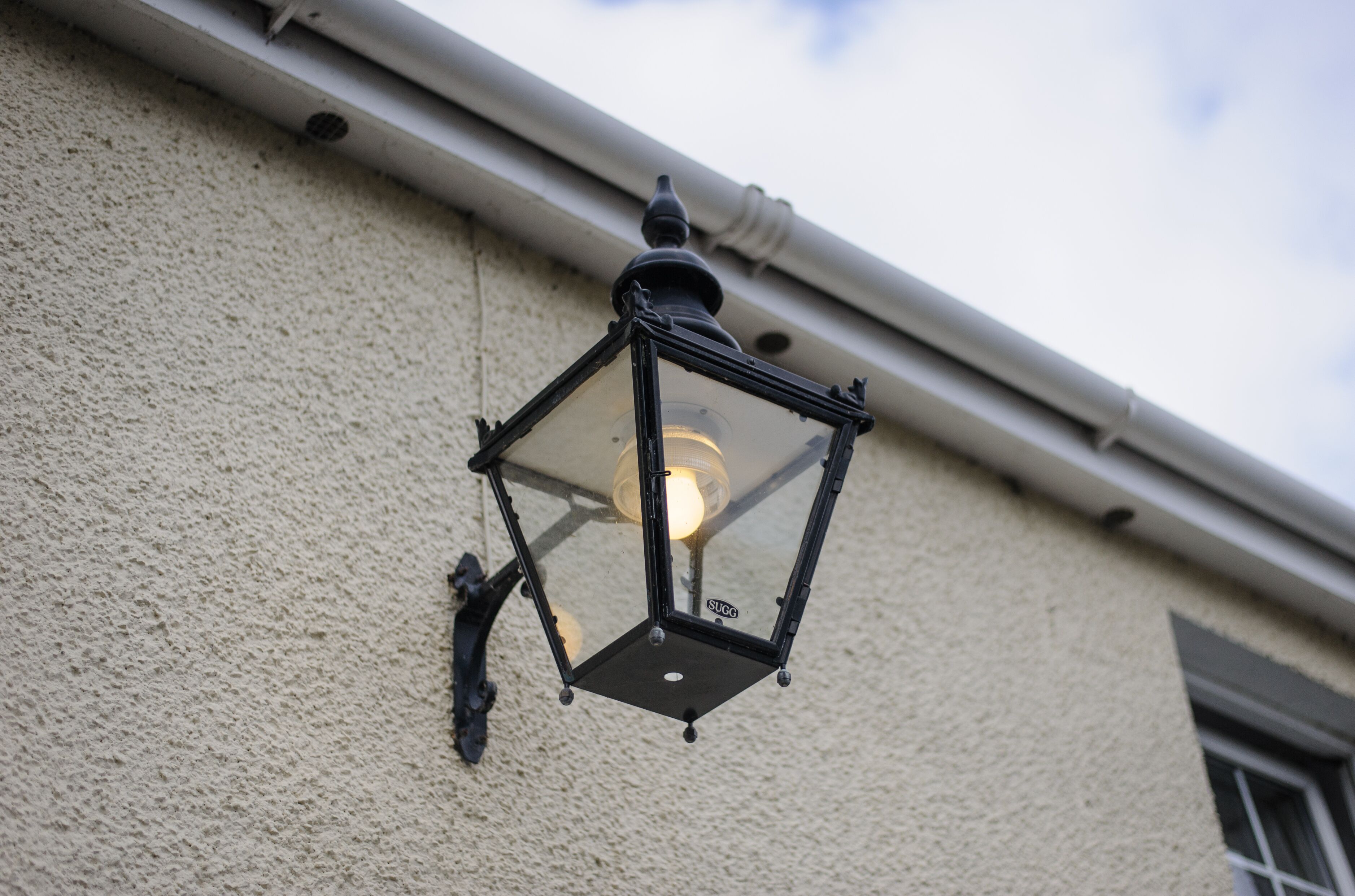 A black lantern hanging on a textured wall.
