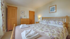 A bedroom with a large bed, wooden wardrobe, and a dresser.