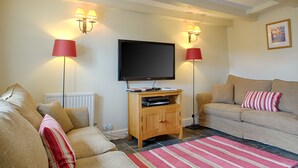 A living room with a flat-screen TV, two lamps, a sofa, and a striped rug.