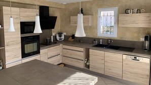 Eine moderne Küche mit Holzausstattung, einem Einbauofen, einer Spüle und Pendelleuchten.